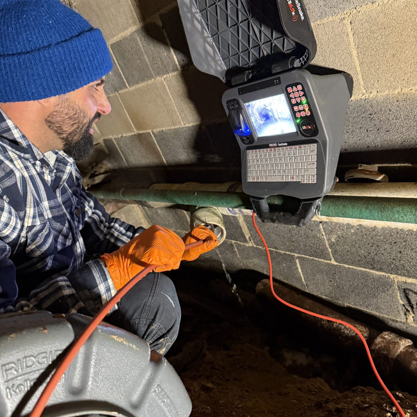 Drainage technician clearing clogged exterior drain for Colonial Park, PA apartment complex after heavy rainstorm